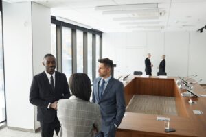 Nonprofit executives greeting each other before a boardroom meeting about fractional versus interim leadership