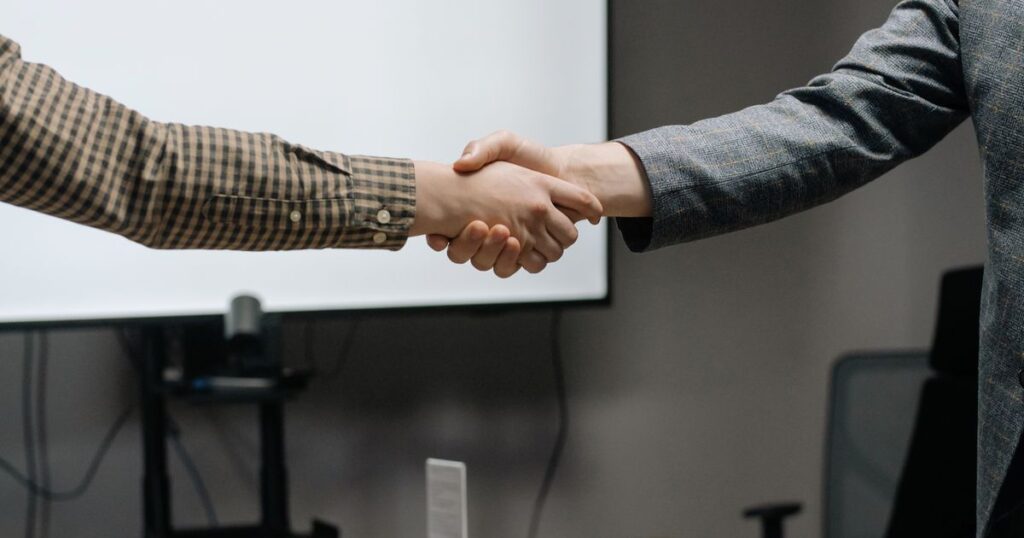 Two professionals shaking hands after a salary negotiation agreement