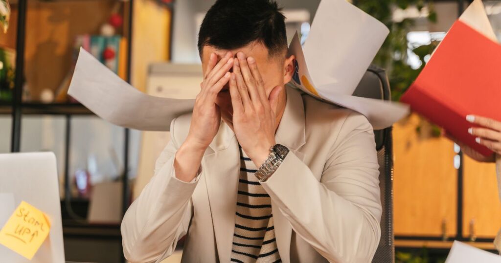 A stressed professional reviewing rejected grant proposal paperwork