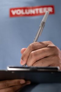 Charity volunteer recording donor details on a clipboard during a community activity