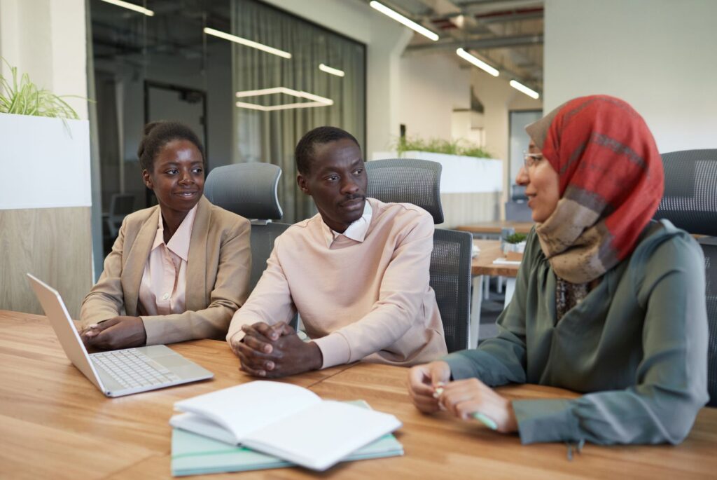 Team members in a collaborative discussion around a wooden table in an office